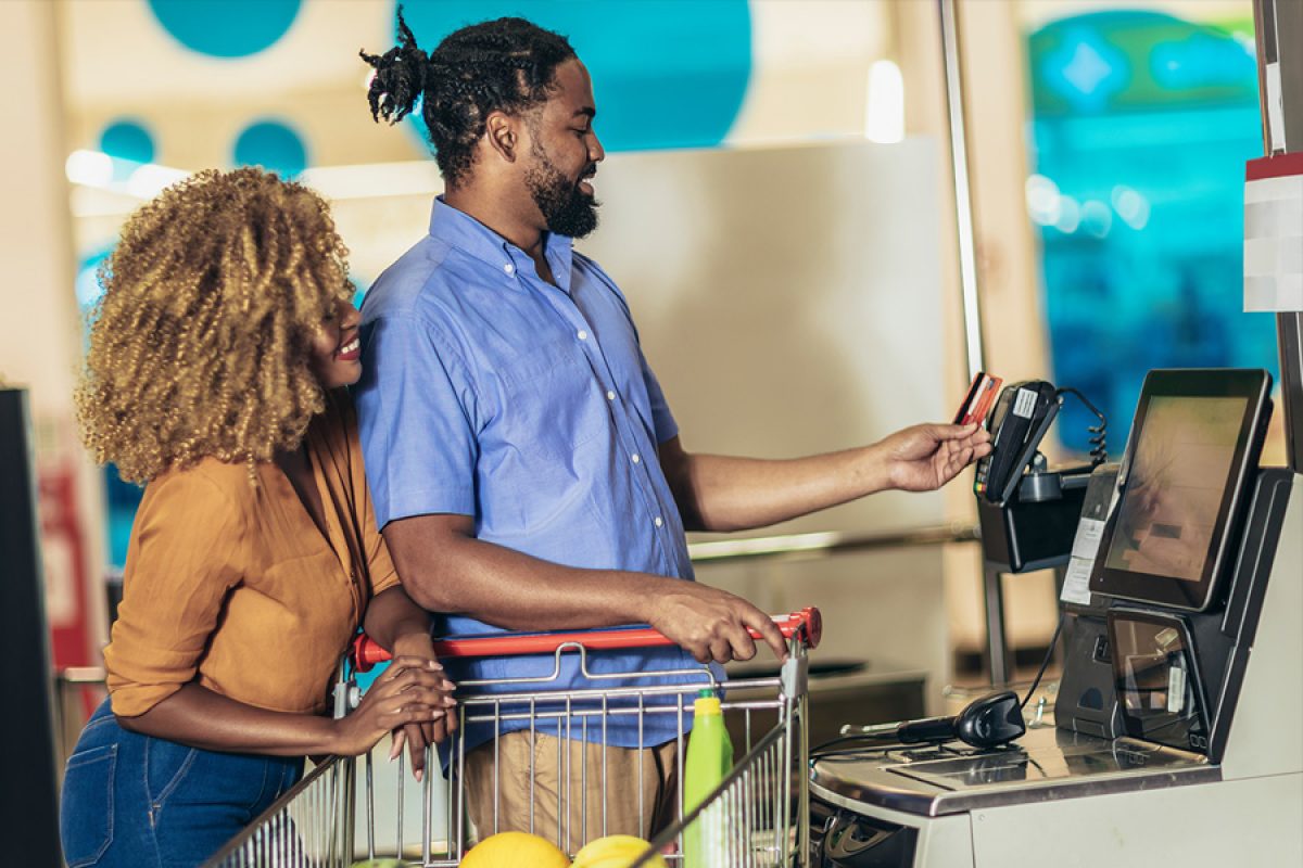 Couple with bank card buying food at grocery store or supermarket self-checkout