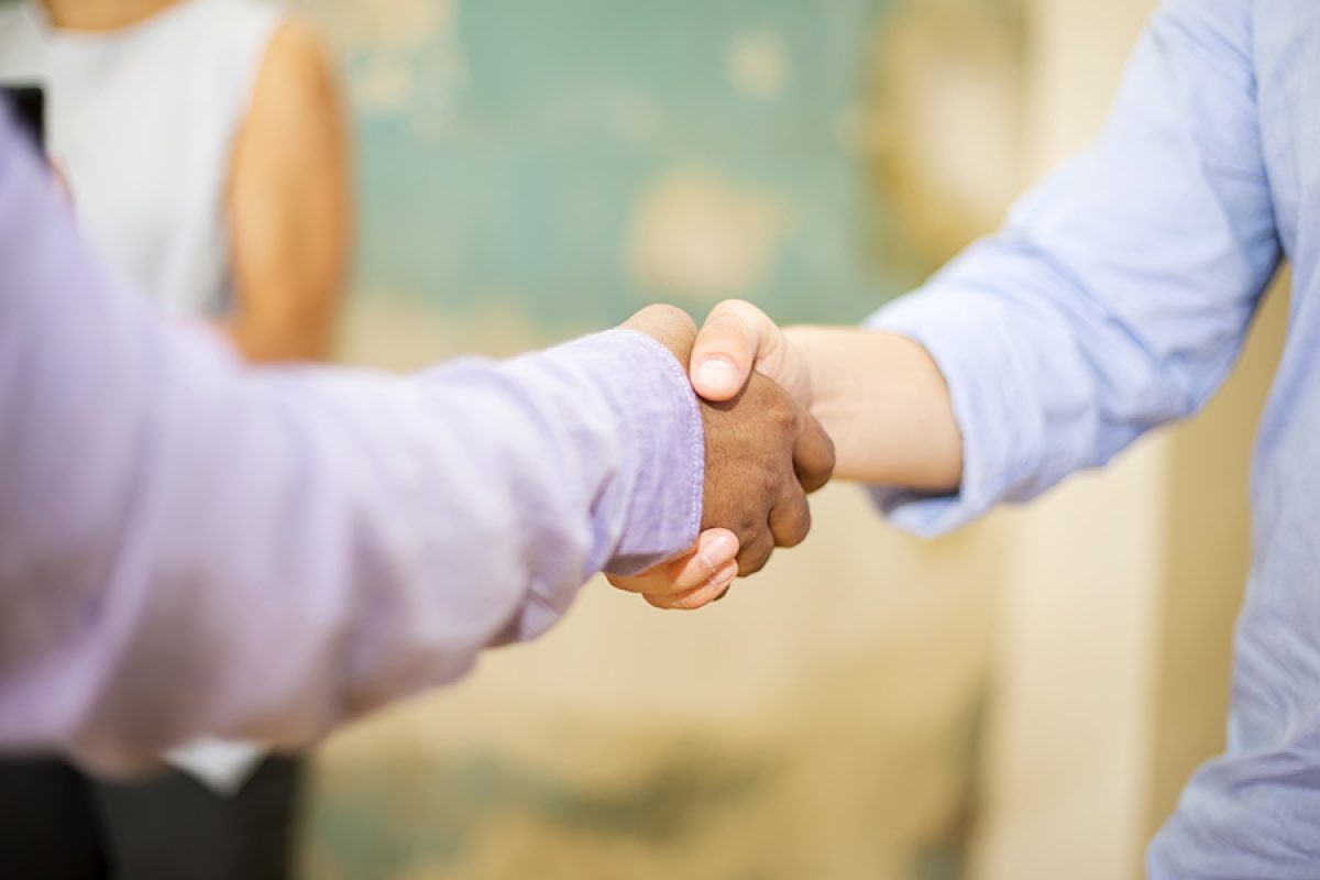 Closeup image of business partners making handshake in grunge office